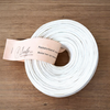 Witte pantalonband op rol, 5 cm breed, op lichte houten tafel &ndash; white trouser waistband roll, 5 cm wide, o