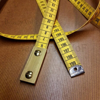 Detail loodcentimeter met messing boekschroeven op hout - Detail of weighted sewing tape with brass binding screws on wood